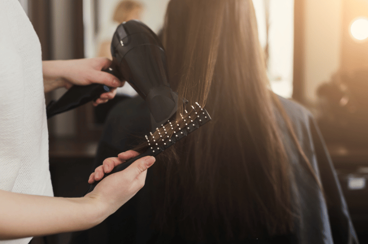 Beautician drying woman's hair after giving a new haircut at home.